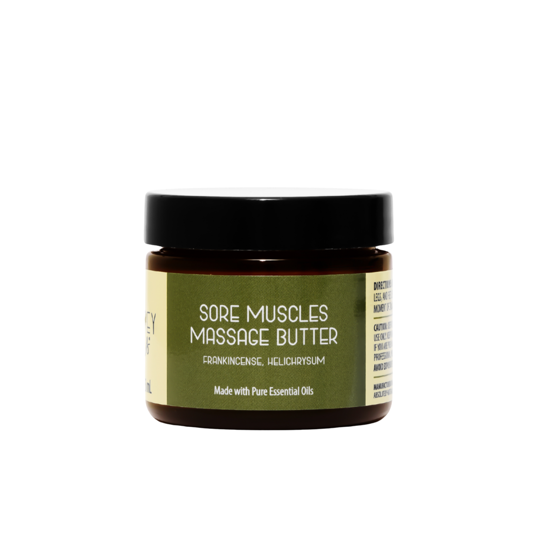 Front view of Kinsley Oils Sore Muscles Massage Butter with frankincense and helichrysum essential oils, packaged in an amber jar with a black lid and olive-green label against a white background.